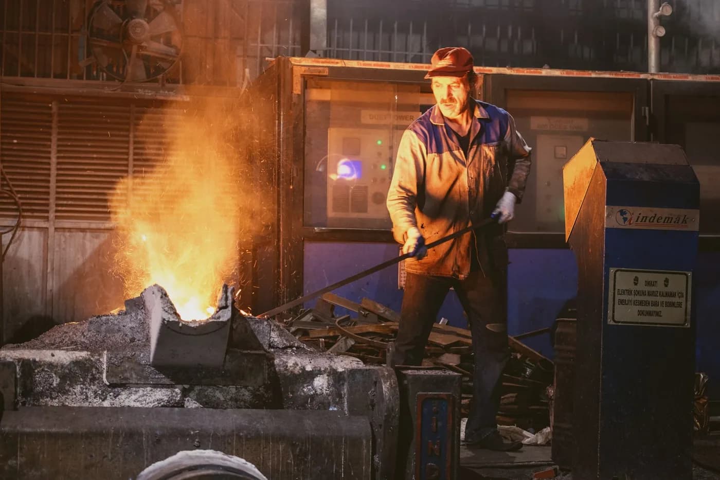 A worker overseeing molten metal in a foundry